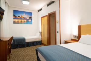马德里Hotel Mora by MIJ的酒店客房配有两张床和一张书桌