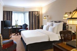 布鲁塞尔沃里克百赛酒店的酒店客房设有一张大床和一张书桌。