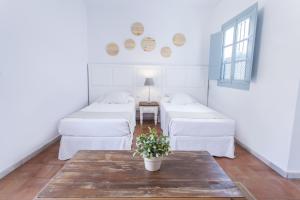 塞维利亚圣克鲁兹套房公寓酒店的一间设有白色床铺和鲜花桌的房间