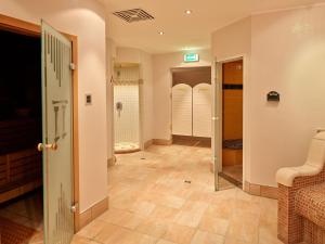 因泽尔Das Wiesgauer - Alpenhotel Inzell的带步入式淋浴间的走廊和铺有瓷砖地板的浴室