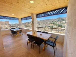 安曼Villa Mira GuestHouse 2 - Downtown Central Amman的客房设有桌椅和大窗户。