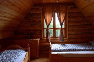 新瓦罗什Milanova koliba Zlatar的小木屋卧室内的两张床,设有窗户