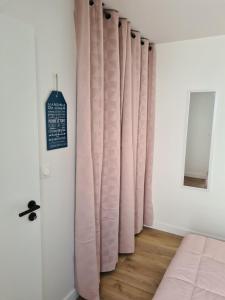 拉罗谢尔Location LA REBELLE - LA ROCHELLE B的一间卧室配有粉红色的窗帘和木地板