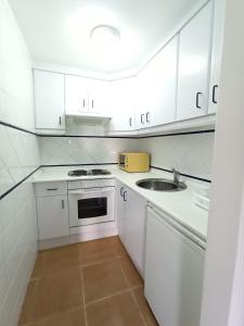 卡内拉岛Acogedor apartamento a 50 metros de la playa的白色的厨房设有水槽和炉灶。