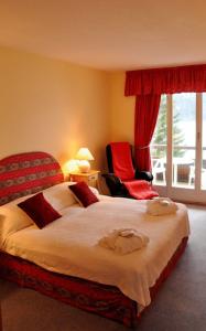 布里恩茨巴伦湖滨酒店的一间卧室配有一张大床和一张红色椅子