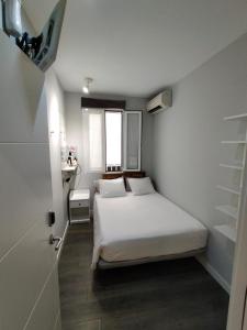 马德里迪斯马德里旅馆的一间小卧室,配有白色的床和窗户