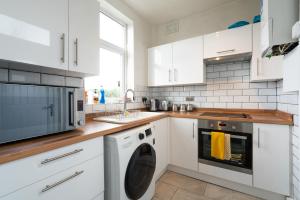 谢菲尔德Spacious & Homely, 4 BR, Parking, Close to Centre的厨房配有白色橱柜、洗衣机和烘干机