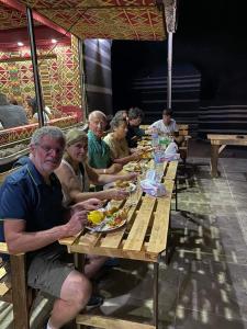 瓦迪拉姆Taj Wadi Rum camp的一群坐在餐桌上吃食物的人