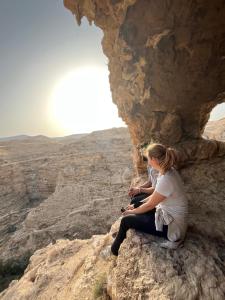 伯利恒Bethlehem City Hostel的两个人坐在沙漠的岩石上