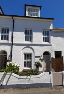 彭赞斯Sanderling - Grade 2 Listed Georgian Townhouse by the sea的前面有长凳的白色房子