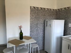 帕拉蒂Flat Boa Vista Beach的厨房配有白色冰箱和带凳子的桌子