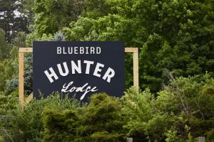亨特Hunter Lodge, a Bluebird by Lark的蓝鸟猎人小屋的标志在树前