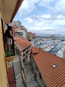 贝梅奥Precioso loft en Bermeo con vistas al mar的站在一个俯瞰码头的阳台上的女人