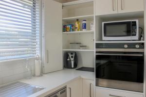 纳皮尔City Centre Escape的厨房配有白色橱柜、微波炉和炉灶。