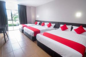 古晋Super OYO 897 iBC36 Business Stay的两张位于酒店客房的床铺,配有红色枕头