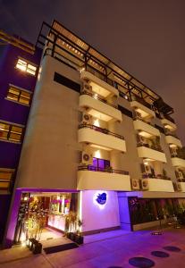 芭堤雅市中心The Weekend Pattaya (Tweet Tweet Nest Pattaya)的一座白色的大建筑,上面有紫色的灯