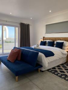 阿曼济姆托蒂Santorini Guesthouse的一间卧室配有一张大床和一张蓝色的沙发