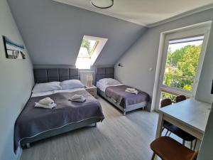 格里兹鲍Pokoje i Apartamenty SOL的一间卧室设有两张床、一张桌子和一个窗口