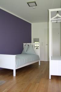 因斯布鲁克Felseck Zimmer的卧室配有白色床和紫色墙壁