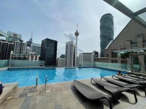 吉隆坡Cormar Suites, Jalan Perak的一个带椅子的大型游泳池,享有城市天际线