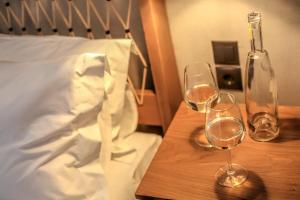 卡兰巴卡Meteora Heaven and Earth Kastraki premium suites - Adults Friendly的两杯葡萄酒放在床边的木桌旁