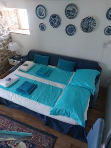 卡什泰拉Water Castle House的卧室配有一张带蓝色枕头和盘子的床铺,墙上挂有