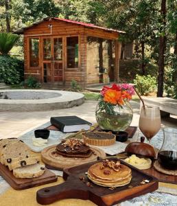 阿尔莫拉Shantiniketan Mountain Home的一张桌子,上面有面包和蛋糕,花瓶