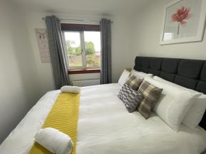 邓弗姆林Pure Apartments Fife - Dunfermline - Pitcorthie的一张白色大床,配有黄色毯子和枕头