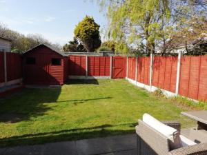 贝提斯顿Bovinda Cottage - By the Beach, Bettystown的一个带红色栅栏和草地庭院的后院