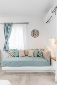纳克索乔拉Arhontiko的白色的房间里设有蓝色的沙发,设有窗户