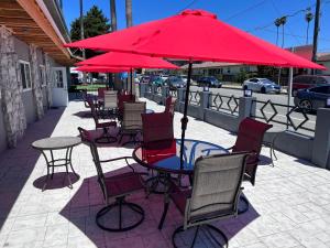 圣克鲁兹冲浪城套房汽车旅馆的一组红色伞下的桌椅