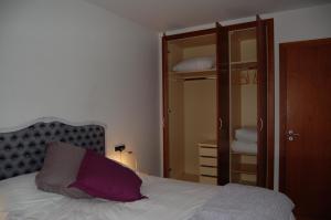 恩坎普APARTAMENT TUCAMP nº6275的一间卧室配有一张带紫色枕头的床和一个衣柜