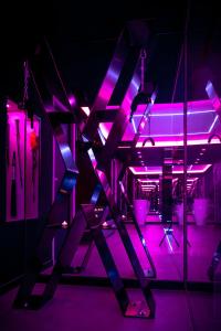 里沃萨尔特LES SECRETS ROOMS, LOVE ROOM DE LUXE AVEC JACUZZI的紫色灯光和配有椅子的舞台的房间