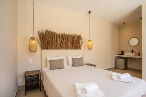 法里拉基Atma Beach Rooms & Suites的卧室配有一张带2条毛巾的大型白色床