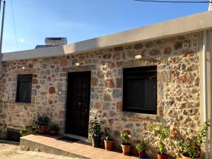 阿基欧斯尼古拉斯Oikia Stone House in seaside Kalo Chorio的前面有盆栽植物的石头房子