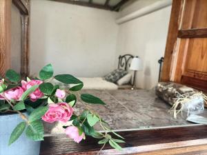 圣克鲁斯-德特内里费Casa rural en el Parque Nacional de Garajonay en la Isla de La Gomera, Alonso y Carmen的一间设有一张桌子的房间,配有一个粉红色玫瑰花瓶