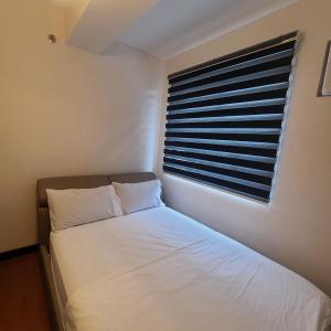 达沃市Magallanes Condo Free Airport Pick Up for 3 nights stay or more的一间小卧室,配有白色的床和窗户