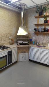 伯迪亚哥Casa na Praia de Maitínga - Bertioga - SP的厨房配有白色橱柜和炉灶烤箱。