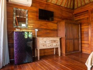登巴萨Pondok Biu的一间带电视和木墙的客厅