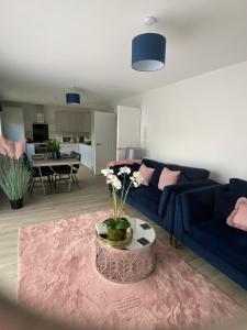 尚克林The Bay house Apartments , shanklin的客厅配有蓝色的沙发和带鲜花的桌子