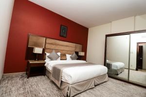 达曼Maskan Almadinah的一间卧室设有一张大床和红色的墙壁