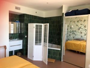 土伦RIOPASSIONS, GRAND T3, BELLE VUE MER的一间带绿色瓷砖墙壁和一张床的卧室以及一间浴室