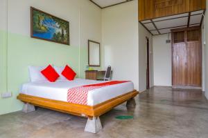 万挠Super OYO Capital O 90548 Sp Venture Resort的一间卧室配有一张带红色枕头的大床