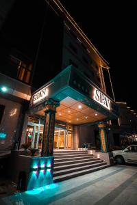 埃尔比勒Sipan Hotel的一座建筑,在晚上前方有标志