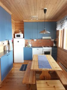 库萨莫Sininen Hetki Cottage的厨房配有蓝色橱柜和木桌