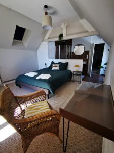 库唐斯La Villégiature的一间卧室配有一张床铺、椅子和一张桌子