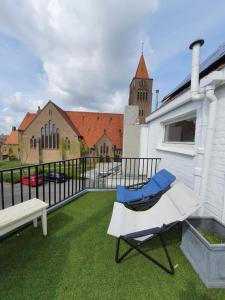 克诺克－海斯特Stijlvolle vakantiewoning Den Baigneur aan zee的阳台配有椅子、长凳和教堂