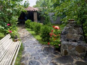 泰拉维Guest House Chiko的一个带长凳和鲜花的花园以及石墙