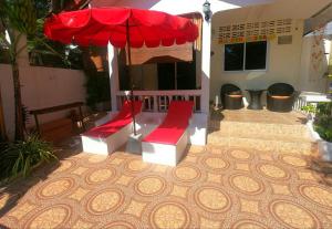 拉迈Lamai villa的庭院设有2个红色长椅和遮阳伞