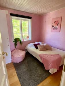 诺尔泰利耶Villa i Norrtälje的一间卧室设有两张粉红色墙壁和窗户